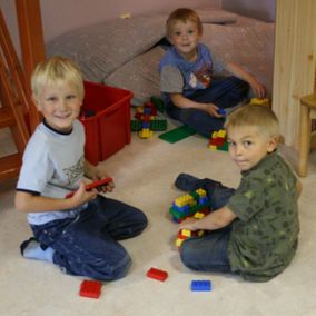 Kolme lasta leikkii duploilla