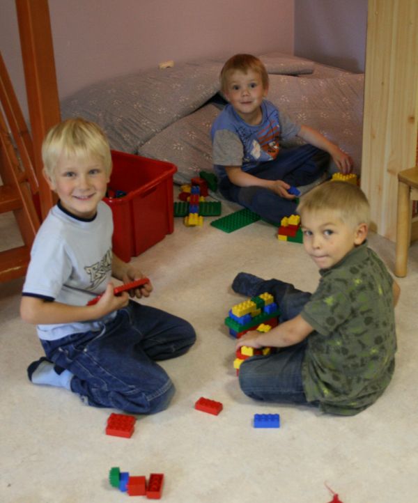 Kolme lasta leikkii duploilla